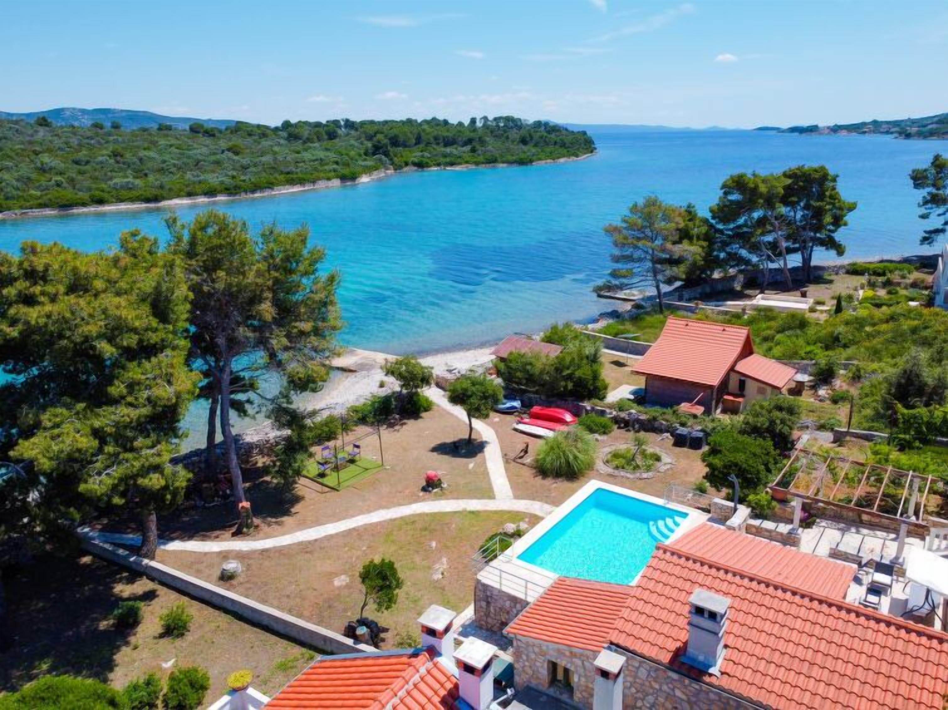 A coastal property with a swimming pool, beach access, and a view of the sea.