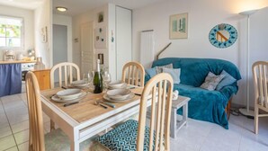 Un comedor con una mesa de madera dispuesta para cuatro, sillas y un sofá azul al fondo.