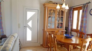 Zona pranzo con tavolo e sedie in legno, una ciotola blu e un mobile con vetri.