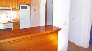 Cucina con mobili in legno, un forno a microonde e un frigorifero.