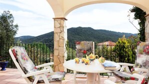 A terrace with a round table and white chairs, overlooking a mountainous landscape. - Cabanyes by Interhome (Calonge)