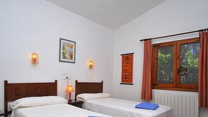 A hotel room with two single beds, a nightstand with a lamp, a window with curtains, and a wall-mounted picture. - Balcon al Mar by Interhome (Jávea)