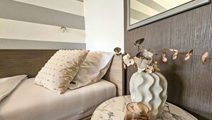 A bedroom with a bed, a vase with flowers, and a candle on a marble table. - Aquanur by Interhome (Vodice/Tribunj)