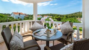 A covered outdoor seating area with wicker chairs and a table, overlooking a scenic landscape. - Aquanur by Interhome (Vodice/Tribunj)