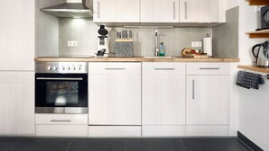A modern kitchen with white cabinetry, stainless steel appliances, and a wooden countertop. - Fürderer by Interhome (Eisenbach)