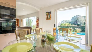 A modern kitchen with a built-in oven and a dining area with a glass table and chairs. - La Petite Afrique by Interhome (Les Issambres)