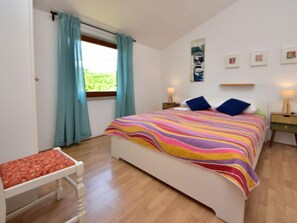 A bedroom with a bed, two bedside tables, a window with curtains, and a view of greenery outside. - Vacation home Kate by Interhome (Novigrad (Zadar))