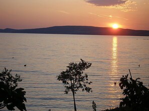 A sunset over a calm body of water with silhouettes of trees and distant hills. - Vacation home Kate by Interhome (Novigrad (Zadar))