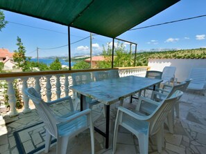 An outdoor patio with a table and chairs, overlooking a scenic view of the sea and hills. - Vacation home Kate by Interhome (Novigrad (Zadar))
