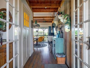 A hallway with wooden floors, white doors, and a dining area with yellow chairs.