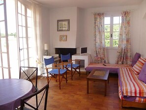 Un salon comprenant un canapé, des fauteuils, une table, un téléviseur et un bureau.