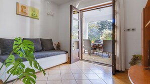 A modern living room with a sofa, a dining area with chairs and a table, and a large window with curtains. - Apartment Anica by Interhome (Zadar)