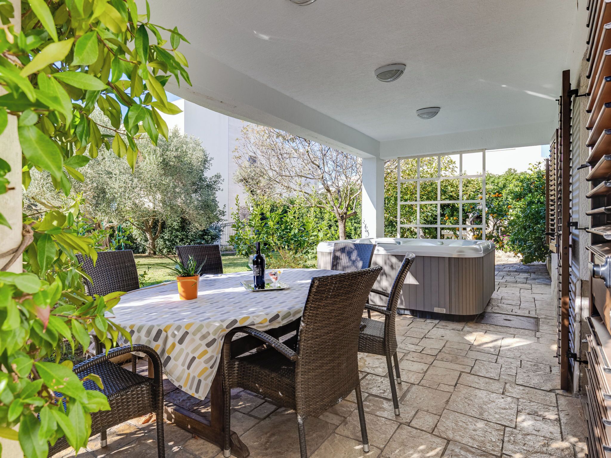 An outdoor patio with wicker furniture, a hot tub, and a stone-tiled floor.