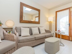 A furnished living room with a sofa, ottoman, and a side table with a lamp.