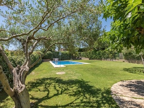 Un jardin avec une piscine, un arbre et un chemin en pierre.