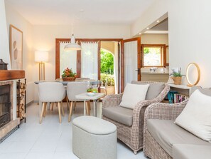 A cozy living room with a fireplace, a dining area, and a wicker sofa.
