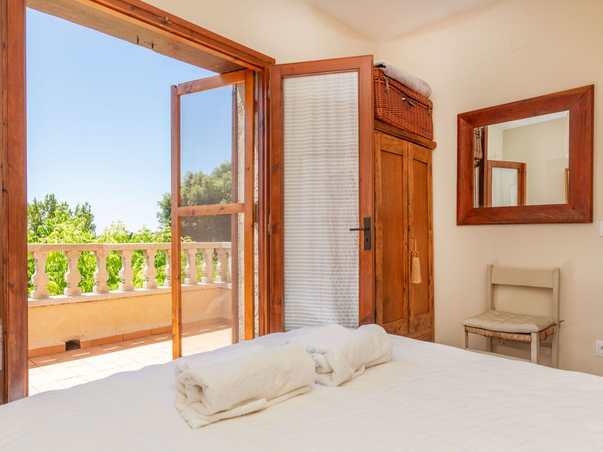 Un dormitorio con cama, puerta de madera, ventana, espejo y balcón.