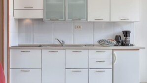 A modern kitchen with white cabinets, a stainless steel sink, and a coffee maker. - Apartment Nika by Interhome (Umag)