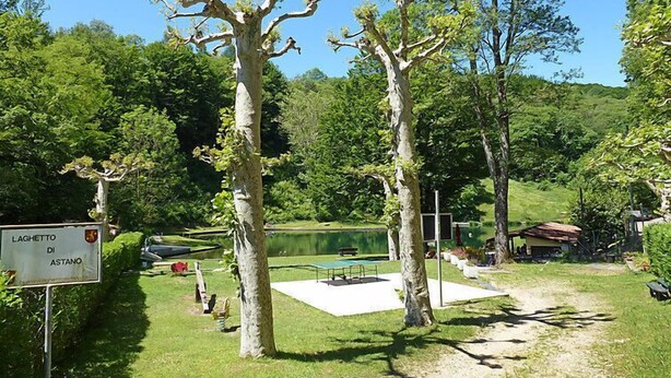 Un parc avec une pancarte indiquant « LAGHETTO DI ASTANO », une piscine et un kiosque.