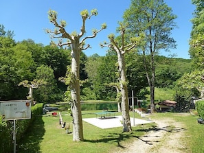 Ein Park mit einem Tennisplatz, Bäumen und einem Schild.