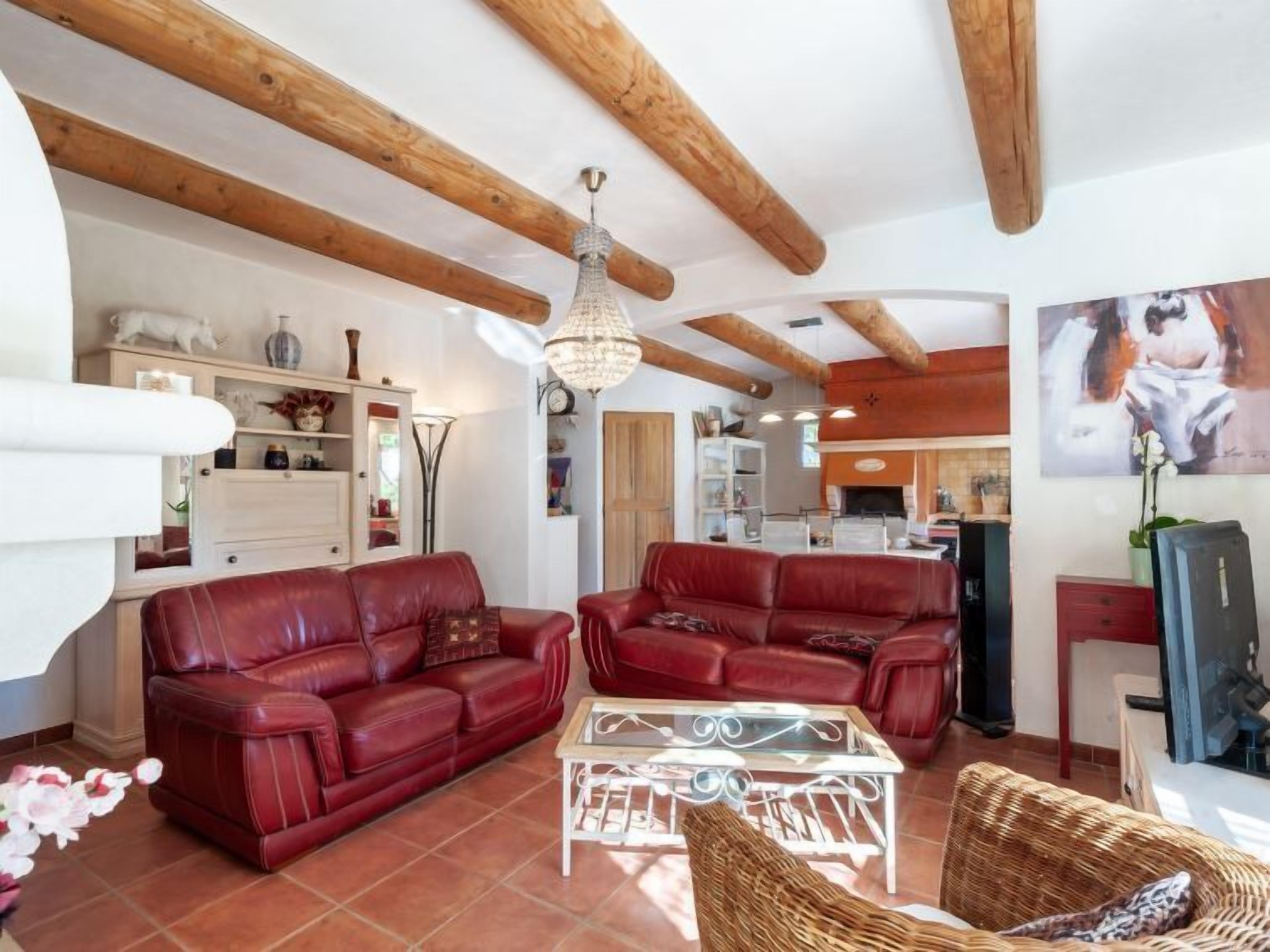 A living room with red leather sofas, a glass coffee table, and a wicker chair.