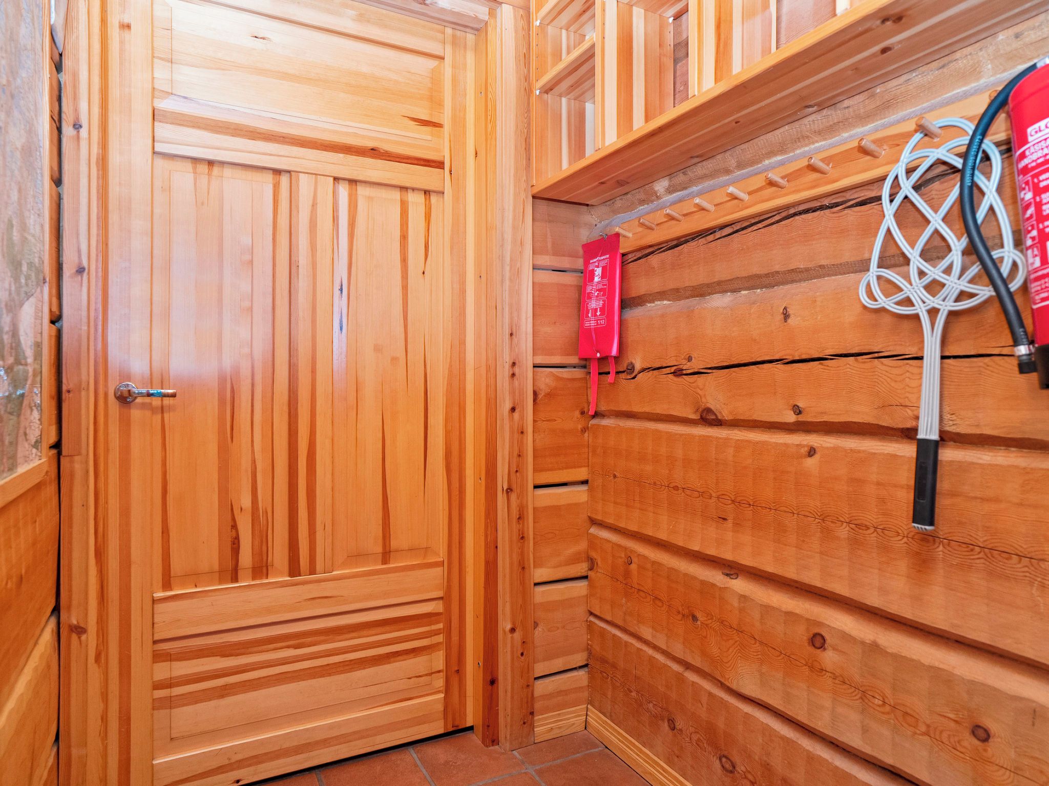 A wooden interior with a door, a wall-mounted rack, and a red sign.