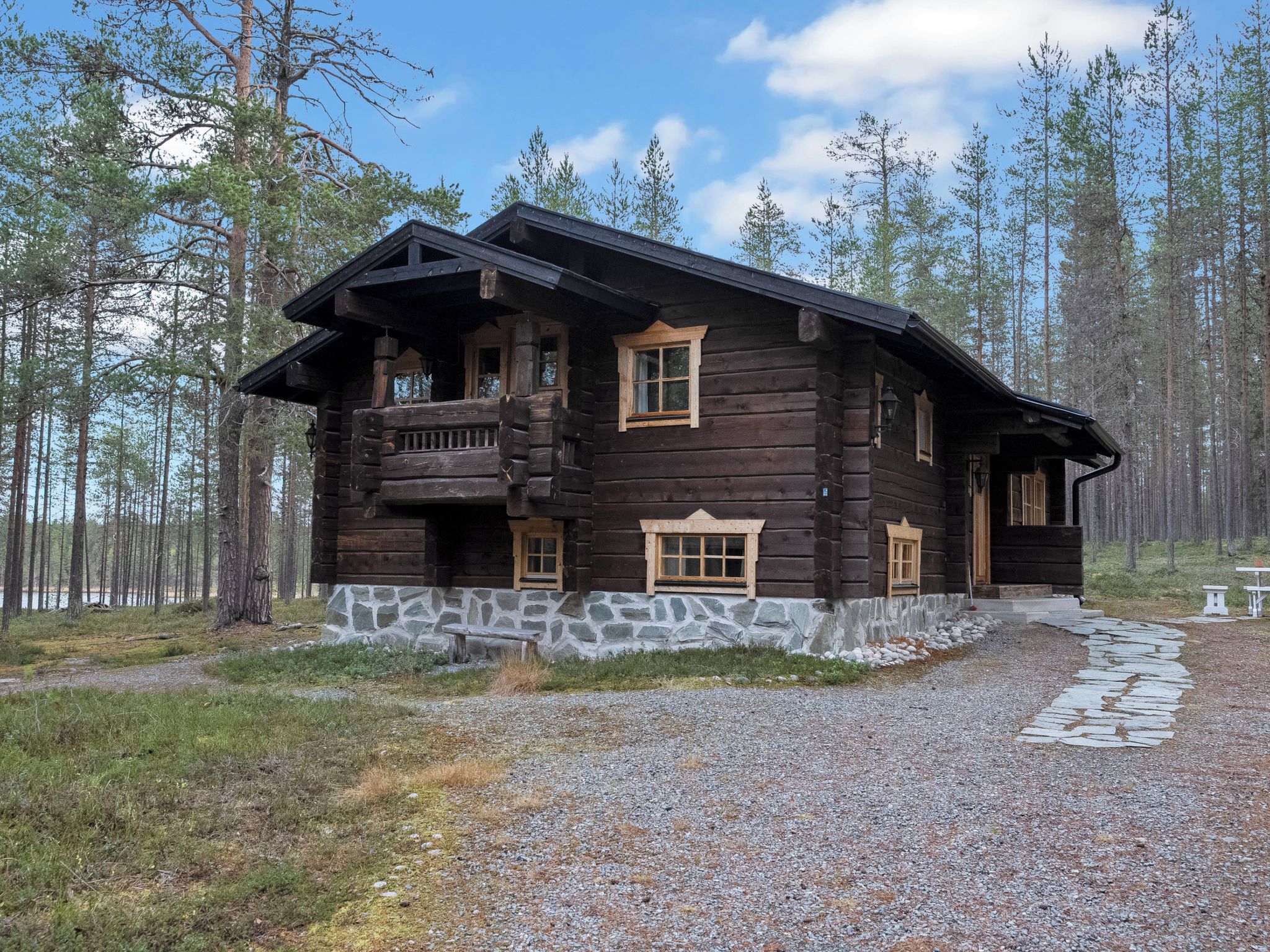 A log cabin with a stone foundation, multiple windows, and a porch.