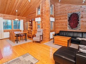 L’intérieur d’une cabane en rondins, avec un coin repas, un canapé et une cheminée.