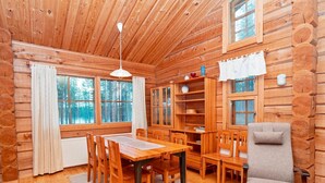 A log cabin interior with a dining area, a reading nook, and a relaxation chair.