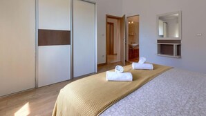A bedroom with a bed, a large mirror, a wardrobe, and a bathroom visible through an open door. - Licardo by Interhome (Štinjan)