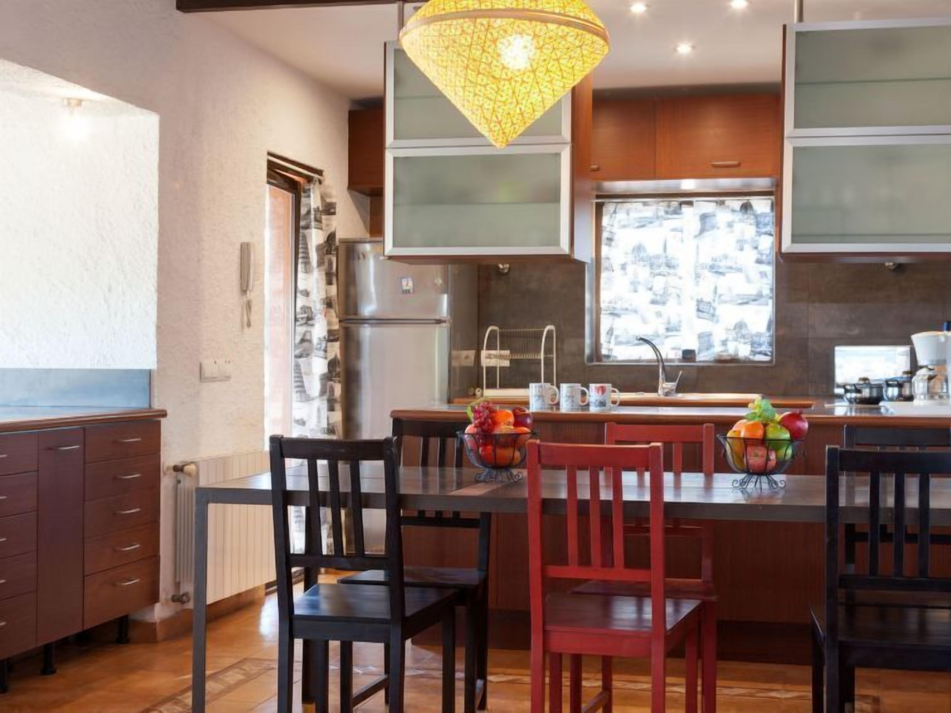 Una cocina moderna con una isla central, armarios de madera y una lámpara colgante.