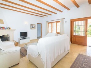 Un dormitorio con cama, televisor, chimenea y puerta que da a un balcón.
