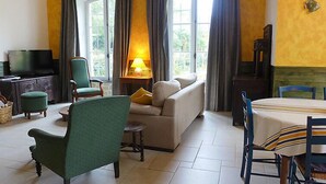 Ein Wohnzimmer mit einer Couch, Sesseln, einem Fernseher und einem Tisch.
