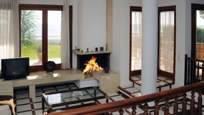 A living room with a fireplace, a television, and a balcony with a view of greenery. - Urb.Maricel by Interhome (Alcanar)