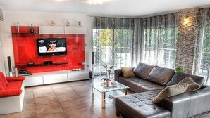 A modern living room with a red entertainment unit, a leather sofa, and a glass coffee table. - Vacation home Nicole by Interhome (Opatija/Pobri)