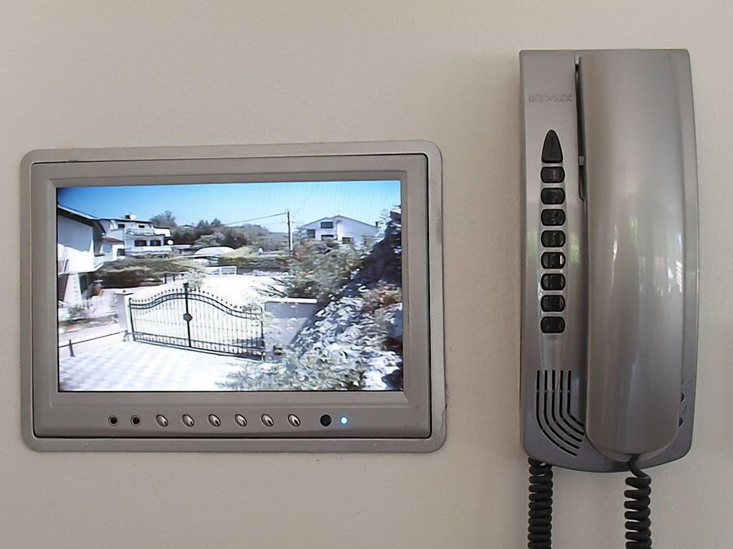 A security camera and a telephone mounted on a wall.