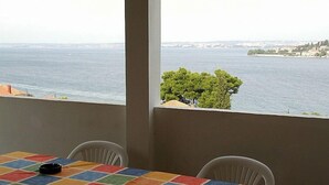 Een kamer met uitzicht op zee, een betegelde tafel en twee stoelen.