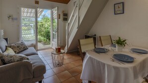 Ein gemütliches Zimmer mit einer Couch, einem Esstisch für zwei Personen und einer Treppe zu einer oberen Ebene.