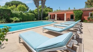 Uma área de piscina com espreguiçadeiras e um espaço de estar coberto.