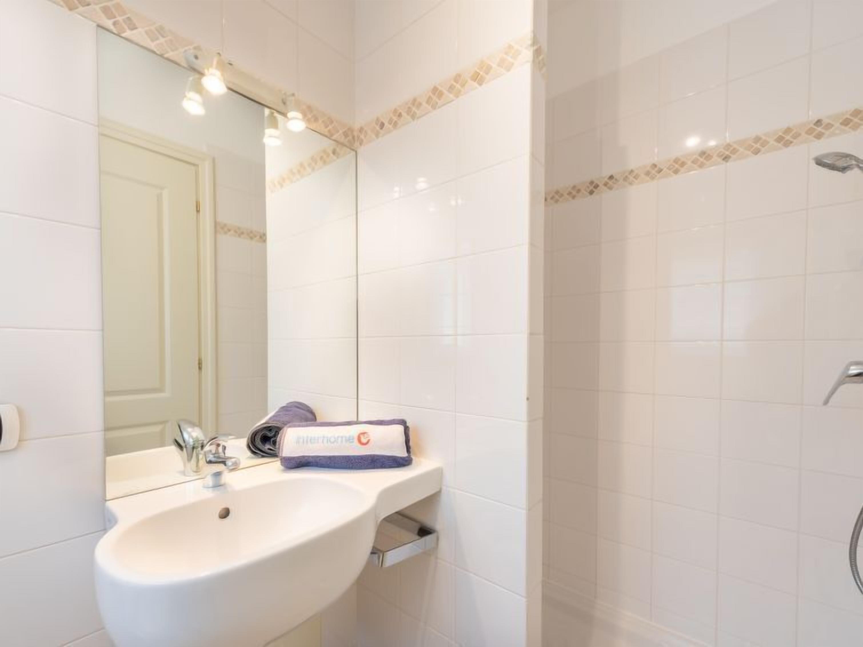 Ein Badezimmer mit einem weißen Waschbecken, einem Spiegel und einer Dusche.