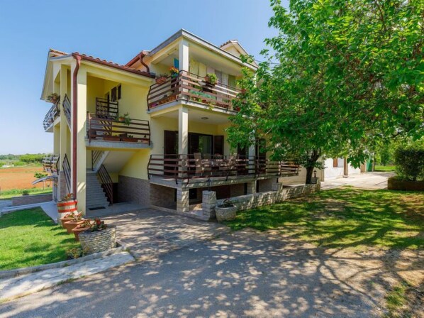 Une maison à deux étages avec un balcon, un chemin de pierre et une pelouse.