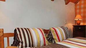 Une chambre avec une tête de lit en bois, un lit avec une literie à rayures, une table de chevet avec une lampe et un mur à carreaux.
