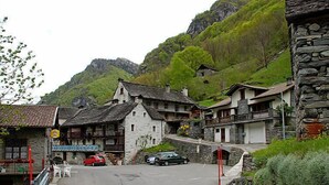Un village aux bâtiments traditionnels en pierre, une rue pavée et un paysage montagneux en toile de fond.