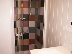 A bathroom with a shower area featuring a checkered tile wall and a white sink.