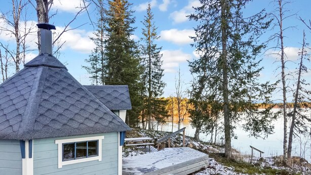 Une petite cabane dotée d’un toit à forte pente, d’une cheminée et d’une terrasse donnant sur un quai.