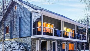 Une maison à deux étages avec une façade en pierre, de nombreuses fenêtres et un balcon.