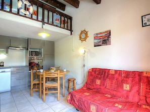 A compact living space with a kitchenette, a dining area, and a red sofa.