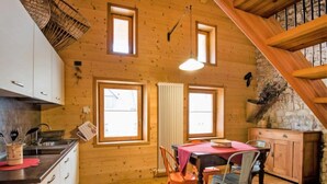A wooden interior with a dining table, chairs, a kitchen area, and a staircase. - Albergo Diffuso - Cjasa Ustin by Interhome (Barcis Lake)