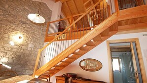 A wooden staircase with a stone wall and a dining area with a table and chairs. - Albergo Diffuso - Cjasa Ustin by Interhome (Barcis Lake)