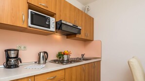 A compact kitchen with wooden cabinets, a microwave, a coffee maker, and a kettle. - Apartment Mare 8 by Interhome (Rab/Kampor)